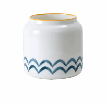 a white and blue vase with a gold rim