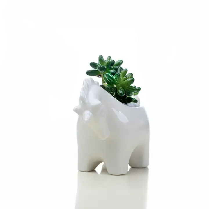 a white elephant planter with a green plant in it