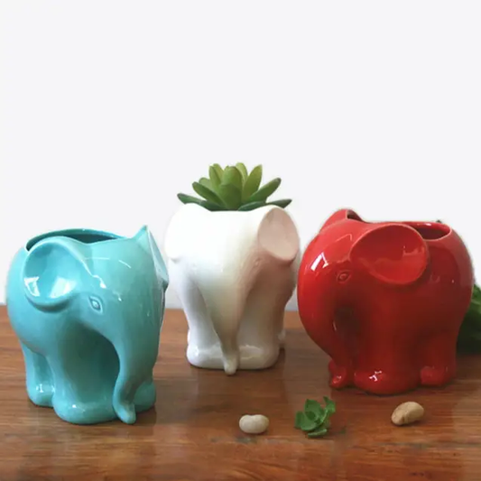 three ceramic elephant planters sitting on a wooden table