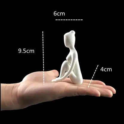 a hand holding a small white figurine on a black background