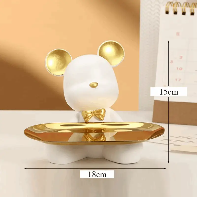 a white mouse figurine sitting on a gold plate