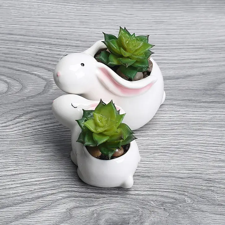 a white bunny planter with a succulent in it