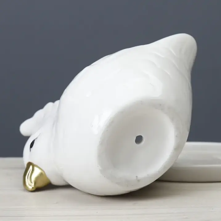 a white bird figurine sitting on top of a white plate