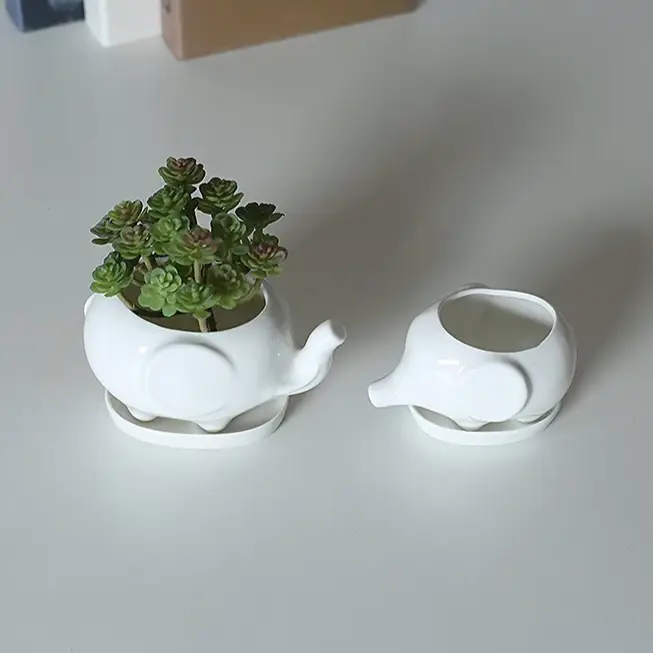 a white elephant planter with a succulent in it
