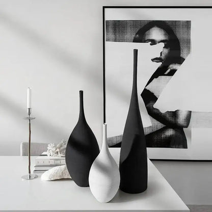 three black and white vases sitting on a table