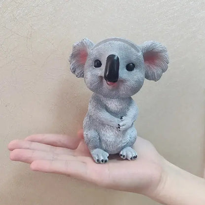 a small toy koala bear sitting on someone's hand