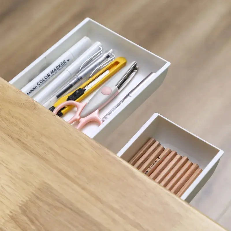 a wooden desk with a drawer containing pens, scissors and pencils