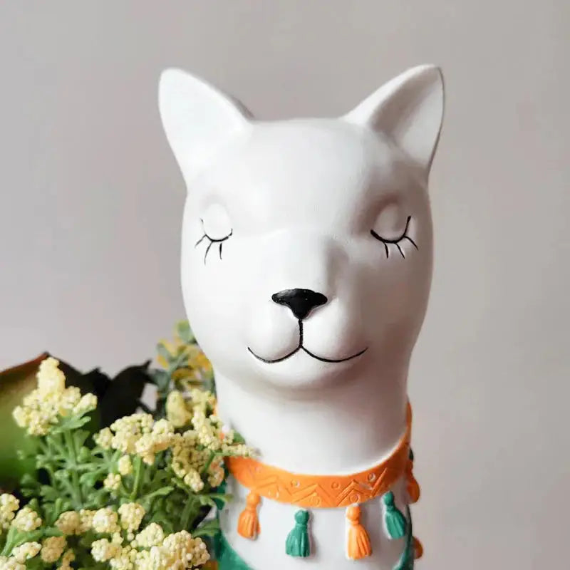 a white ceramic cat with eyes closed next to a bouquet of flowers