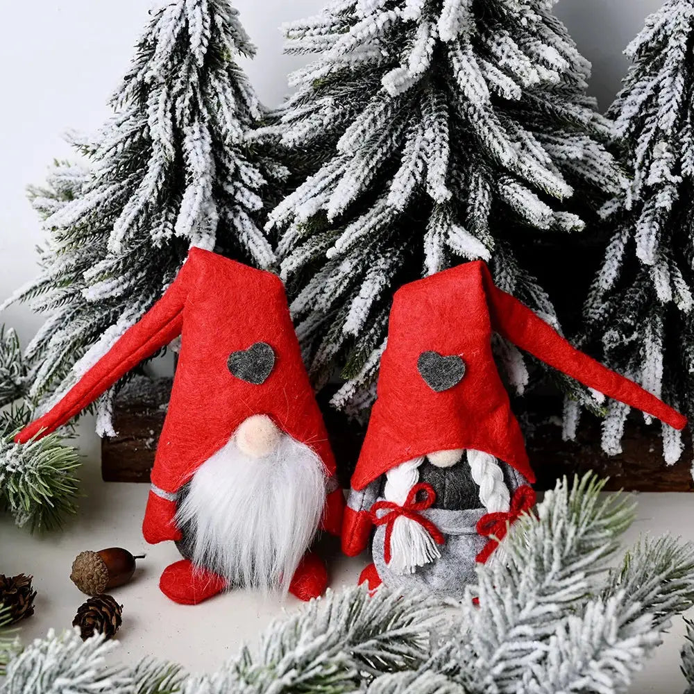 a couple of red gnomes sitting next to a christmas tree