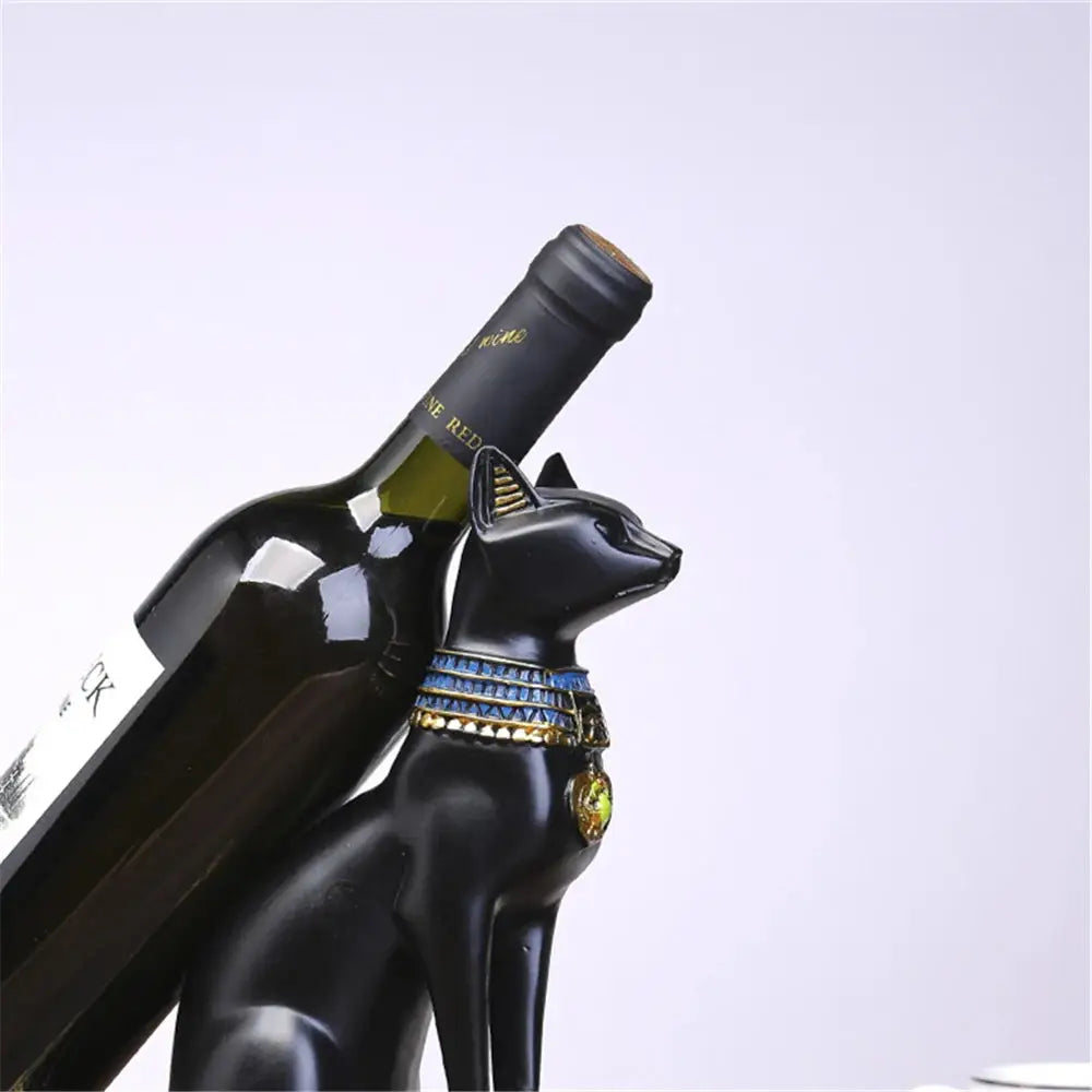 a black cat figurine holding a bottle of wine