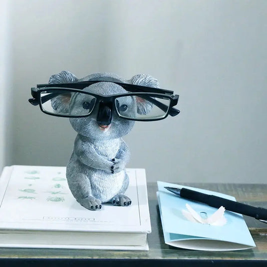 a toy koala wearing glasses sitting on top of a book