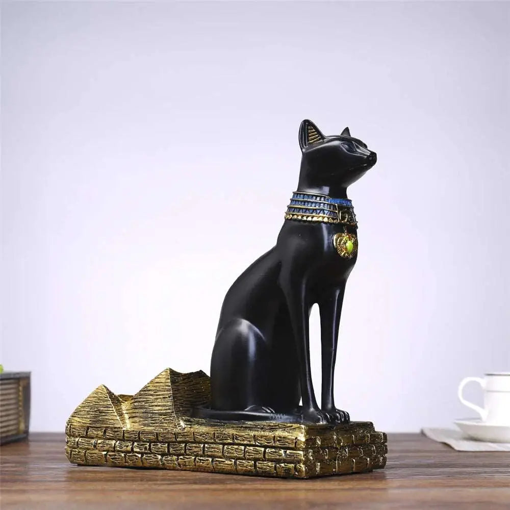 a black cat statue sitting on top of a wooden table