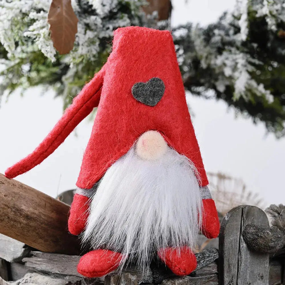 a red and white gnome sitting on top of a wooden fence