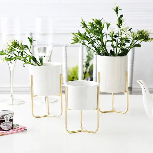 three white vases with plants in them on a table