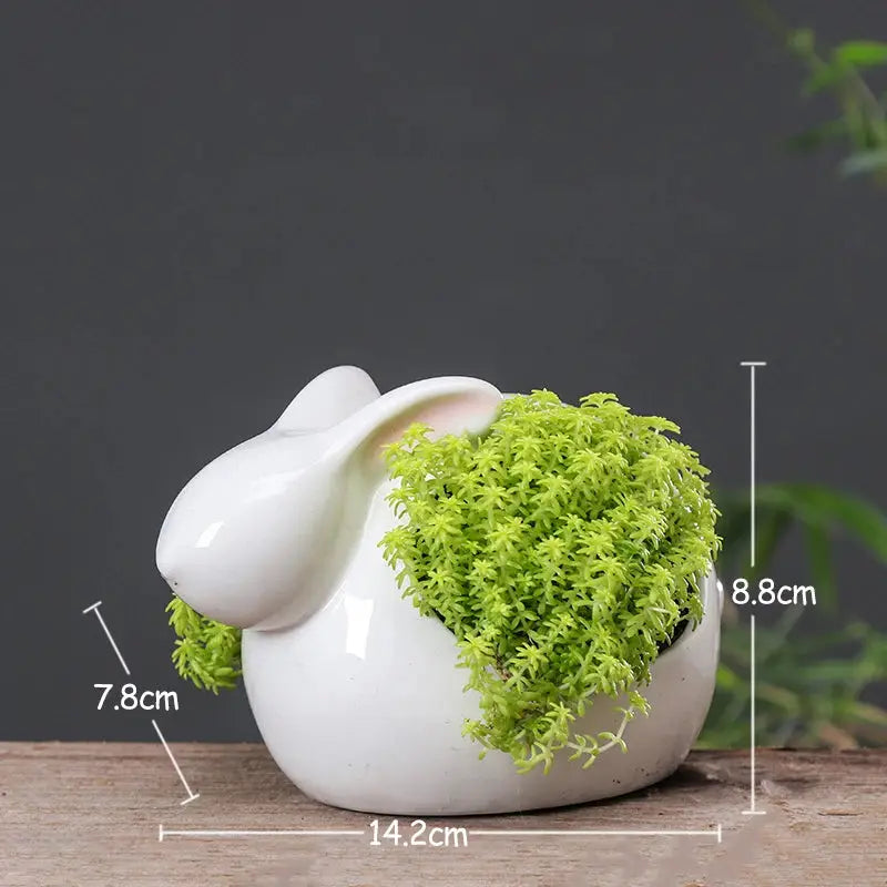 a white bunny planter with moss in it