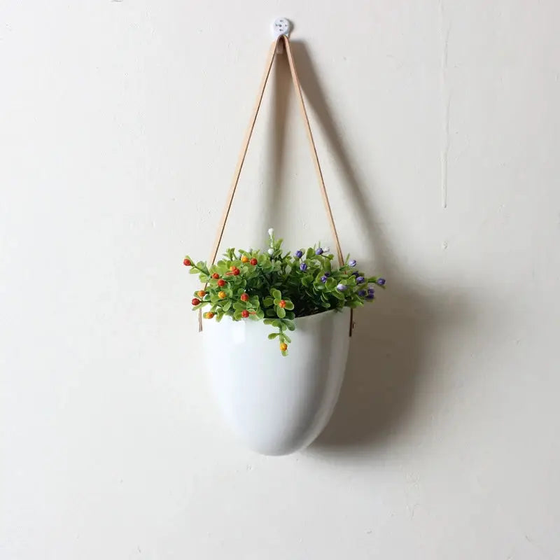 a white hanging planter with flowers in it