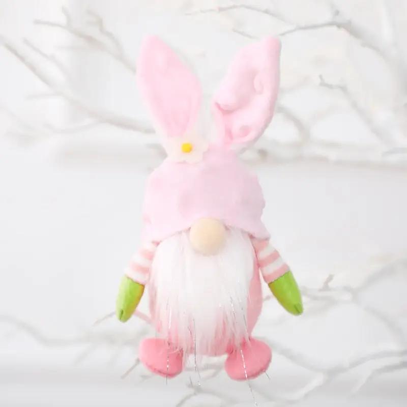 a pink and green stuffed animal hanging from a tree