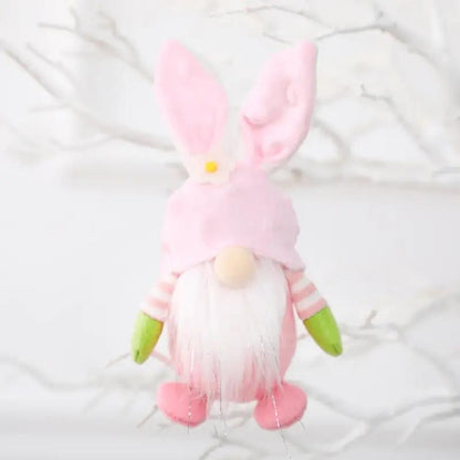 a pink and green stuffed animal hanging from a tree