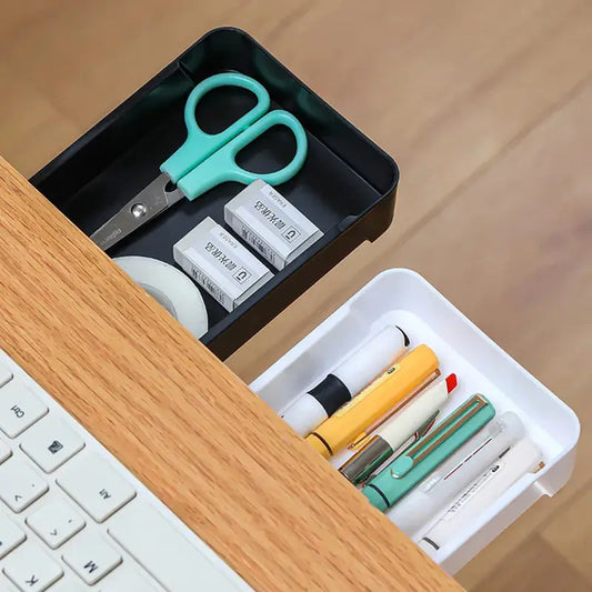a wooden desk with a keyboard and a drawer with pens and scissors