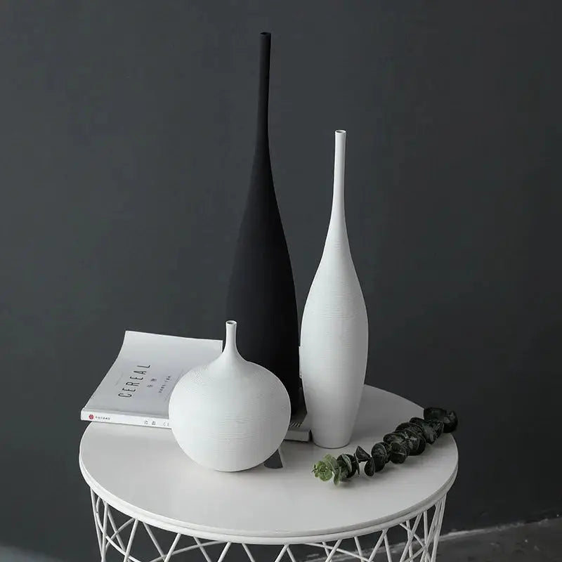 three white and black vases on a white table