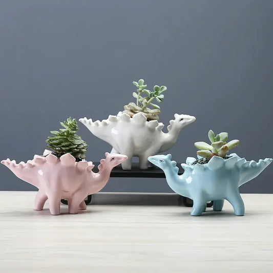 three ceramic dinosaur planters sitting on top of a table