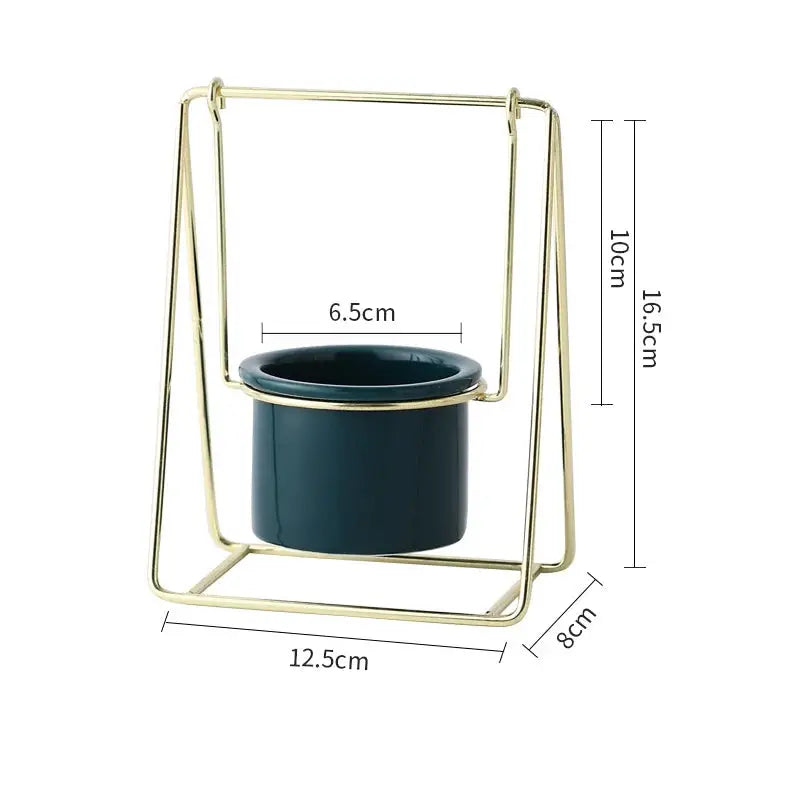 a gold metal holder with a black pot on it