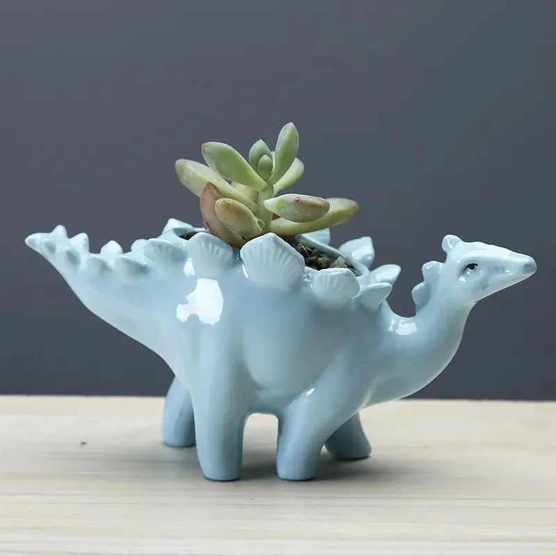 a ceramic planter shaped like a dinosaur with a succulent in it