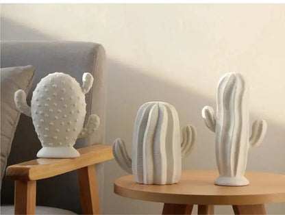 a couple of white cactus statues sitting on top of a wooden table
