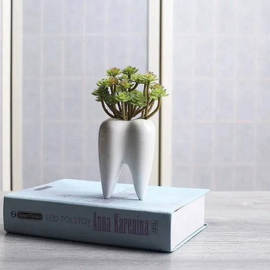 a tooth shaped planter on top of a book