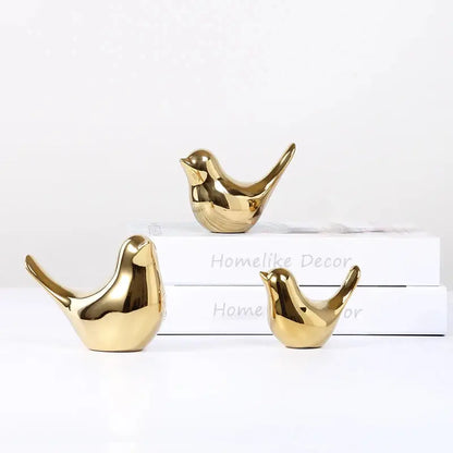 a couple of gold birds sitting on top of a white box