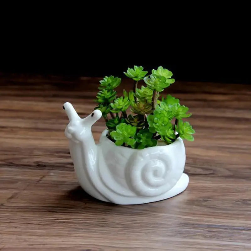 a white ceramic snail planter with a green plant in it