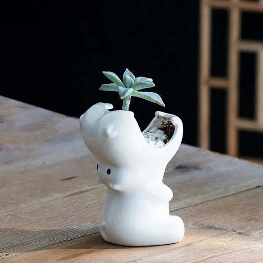 a small white elephant planter on a wooden table