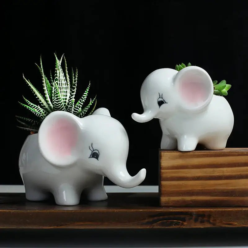 a couple of white elephants sitting on top of a wooden table