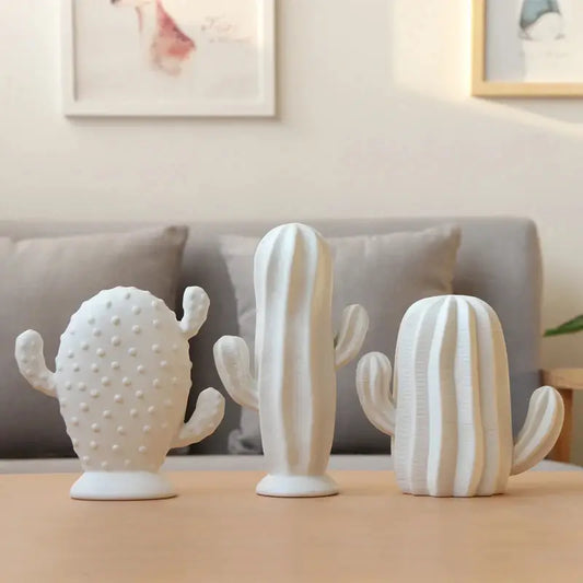 three ceramic cactus sculptures on a table in a living room