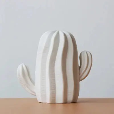 a white ceramic cactus sitting on top of a wooden table