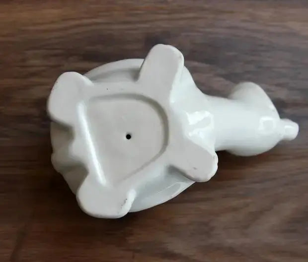a white ceramic elephant toothbrush holder on a wooden table