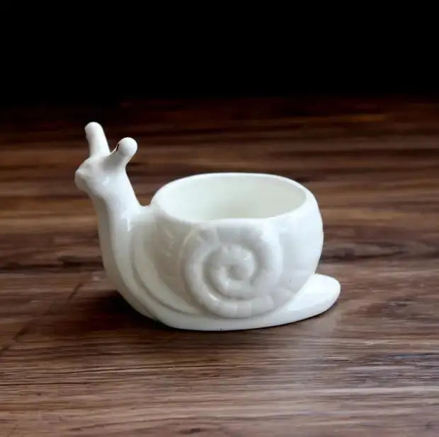 a white ceramic snail cup on a wooden table