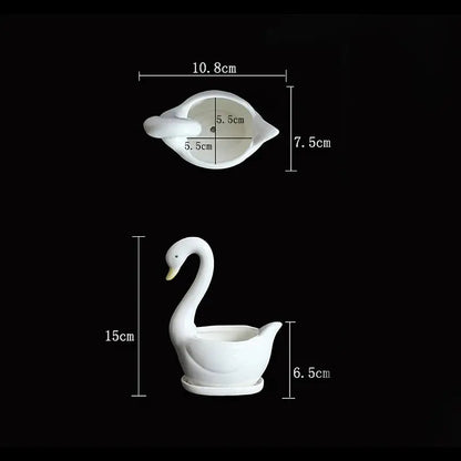 a white swan shaped bowl sitting next to a white swan shaped bowl