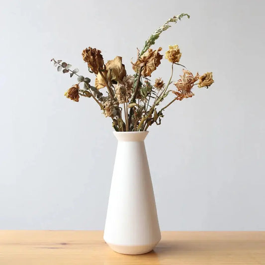 a white vase with dried flowers in it