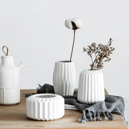 three white vases sitting on top of a wooden table