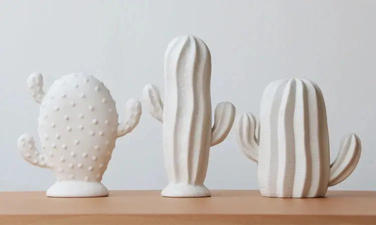 three white ceramic cactus sculptures on a table