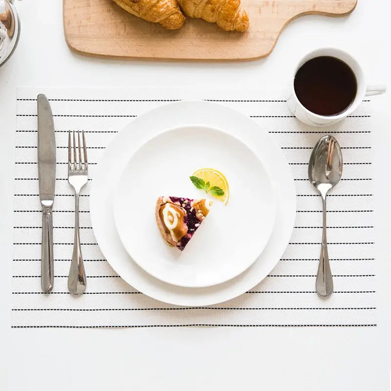 a white plate topped with a pastry next to a cup of coffee