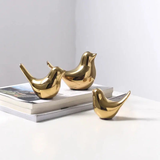 a couple of gold birds sitting on top of a book