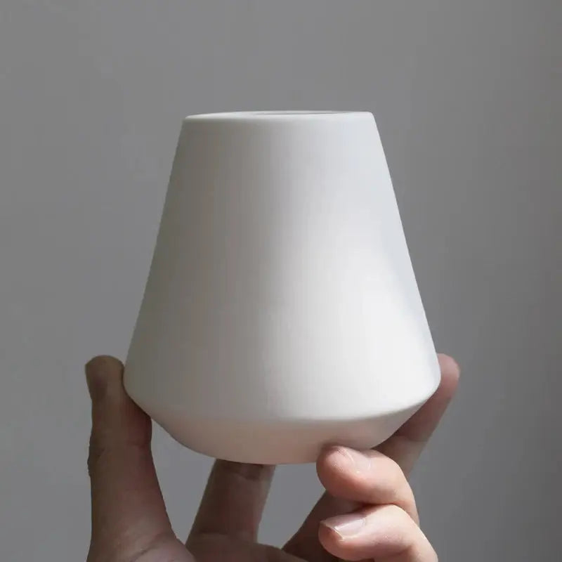 a person holding a white vase in their hand