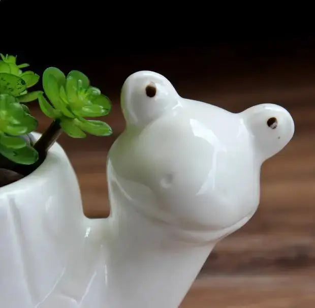 a white ceramic bear planter with a plant in it
