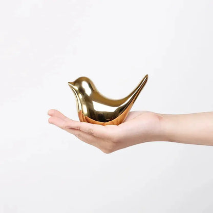 a hand holding a gold bird shaped object