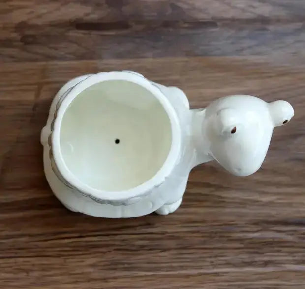 a white elephant shaped cup sitting on top of a wooden table