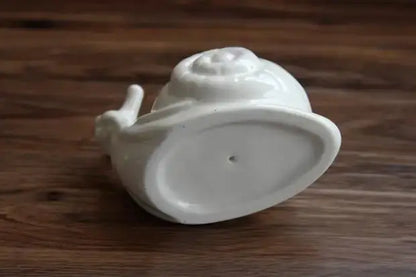 a white porcelain teapot on a wooden table