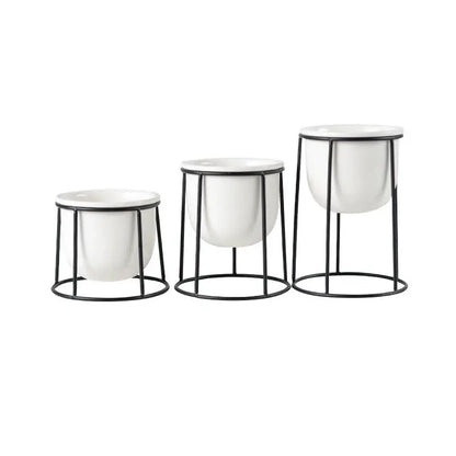 three white vases sitting on top of a metal stand