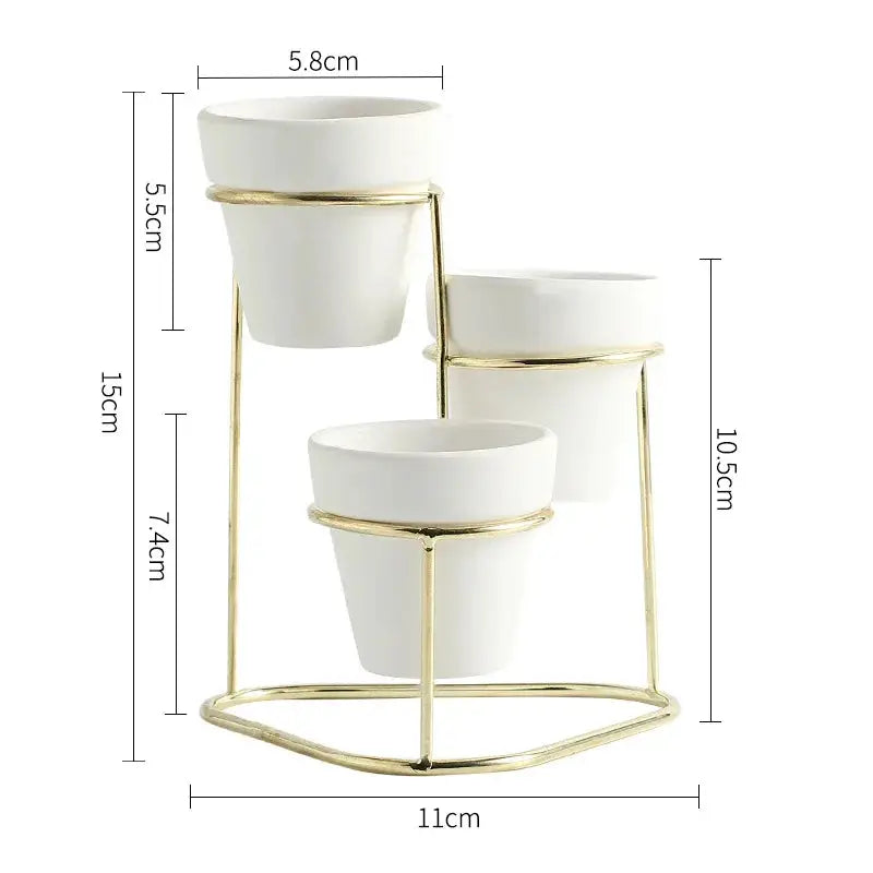 three white planters sitting on a gold stand